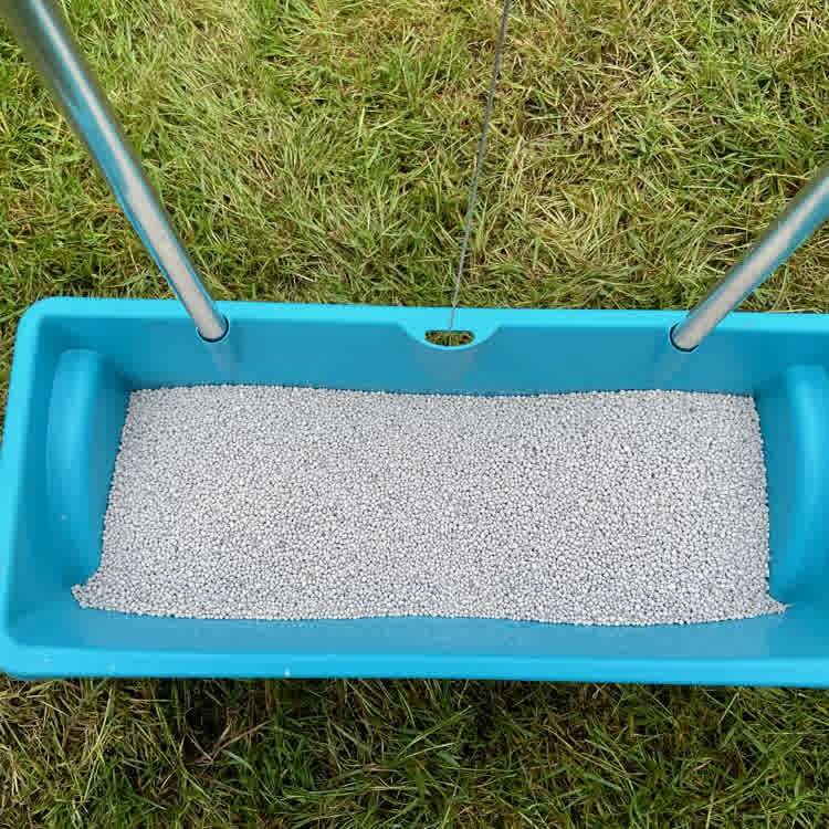 Drop spreader on lawn with pre-seeding fertiliser